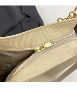 Macro detail of golden zipper puller and internal pocket in beige fabric tote bag