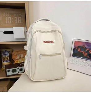 Detail of cream white backpack with red embroidery on a desk in a study setting