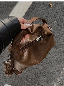 Gros plan détaillé du sac en cuir plissé marron foncé avec texture grainée et nœud tressé