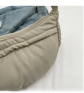 Detail of beige crescent nylon tote showing smooth zipper and reinforced double stitching