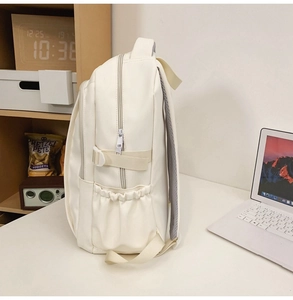 Detail view of the cream backpack side pocket, elastic strap, and breathable mesh strap