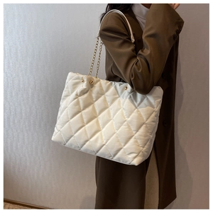 Close-up of the white quilted nylon fabric and elegant gold chain strap on the tote bag