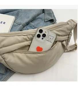 Detail of beige nylon crossbody bag showing spacious interior with a smartphone storage