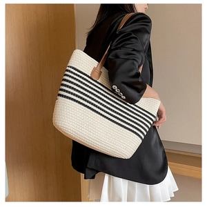 Close-up of a striped woven tote bag featuring brown leather shoulder straps