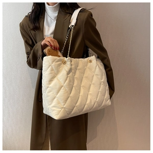 Detail of white quilted nylon tote bag showing spacious interior and golden chain strap
