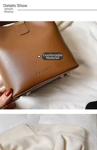 Detail of brown leather bucket bag showing MACGHEE logo and golden protective bottom studs