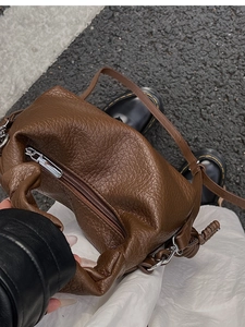 Vue POV du sac à main en cuir marron avec détails plissés et nœuds sur la rue