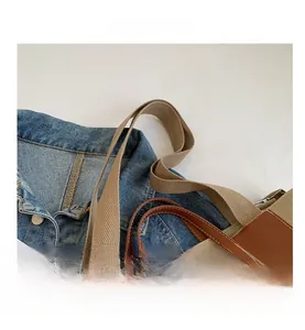 Detail of canvas tote bag showing brown leather handles and adjustable fabric strap