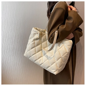 Quilted chain tote bag in beige nylon fabric shown on model for daily commuting style