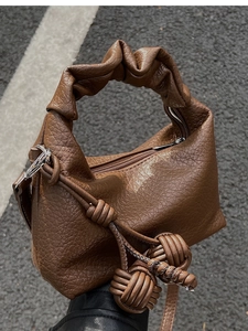 Gros plan d'un sac en cuir marron texturé avec une poignée froncée au style rétro