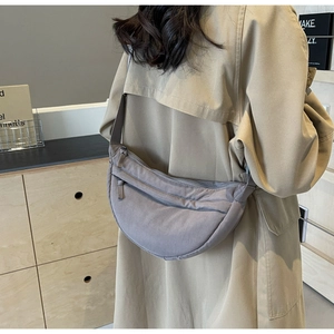Dettaglio della borsa a mezzaluna in nylon grigio-viola indossata con tracolla regolabile
