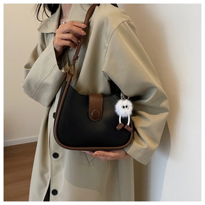 Detail of minimalist semi-circle shoulder bag in black PU leather with monster charm