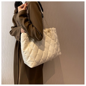 Detail of white quilted nylon tote bag with golden chain strap and magnetic closure
