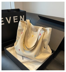 Close-up of beige tote bag with colorful letter embroidery and KFRBAG leather brand tag