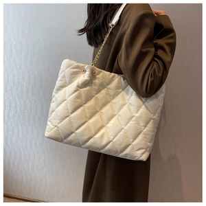 Macro shot of white quilted nylon tote bag featuring gold chain strap and metal details