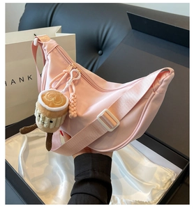 Detailed shot of a pink crescent nylon crossbody bag with a plush coffee cup charm