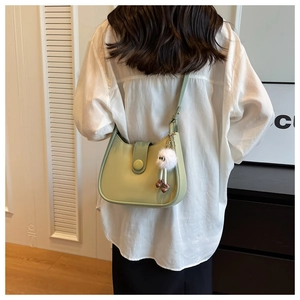 Detail of light green saddle bag with smooth leather finish and cute plush monster charm