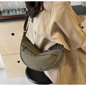 Detail of olive green crescent nylon bag featuring quilted texture and zip pocket