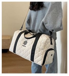 Detail der weißen gesteppten Reisetasche mit seitlicher Reißverschlusstasche und Gurt