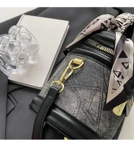 Détail du sac seau en denim gris avec cuir noir et foulard en soie décoratif