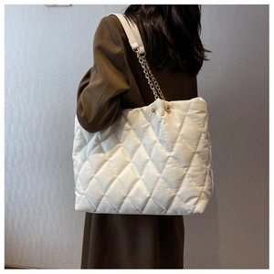 Rear view of a white quilted nylon tote bag with golden chain straps and ball charm detail
