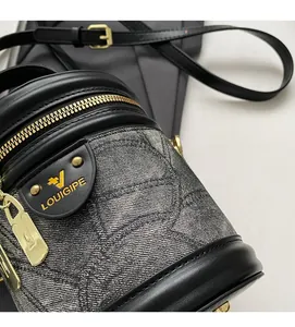 Gros plan d'un sac seau en denim gris avec bordures en cuir noir et logo doré chic