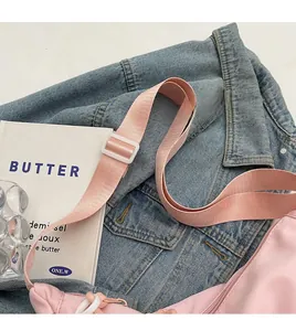 Close-up of adjustable pink nylon strap with white buckle on a crossbody bag
