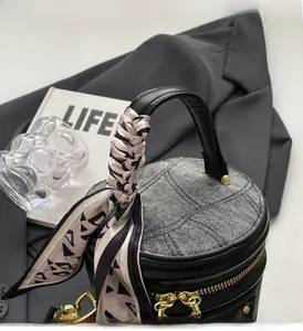 Détail d'un sac seau en denim gris avec matelassage et poignée ornée d'un foulard