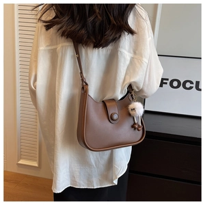Detail of vintage brown shoulder bag with white plush charm and leather buckle detail