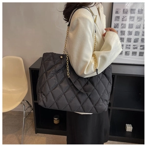 Close-up of black quilted nylon tote bag featuring classic diamond stitching and chain strap
