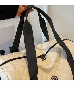 Detail der gesteppten cremeweißen Reisetasche mit schwarzen Webgriffen und Metallreißverschluss