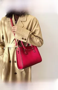 Detailed close-up of red lychee pattern handbag with golden metal hardware and ring handle