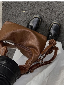 Détail du sac hobo en cuir grainé marron avec poignée nouée et fermeture éclair argentée