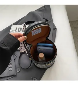 Vue intérieure du sac rond en cuir noir montrant l'espace pour téléphone et parfum