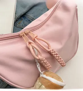 Detail of pink nylon dumpling bag featuring dual smooth zippers and woven pull cords
