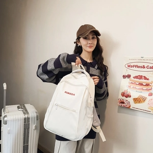 White student backpack with red RUIKEDA logo held by a model in a natural indoor setting
