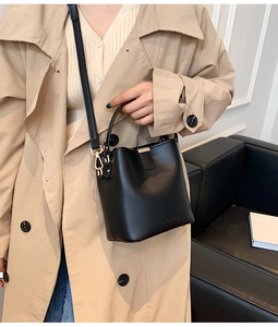 Close-up of black leather bucket bag showing golden hardware and adjustable strap