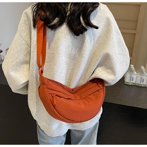 Macro shot of a casual orange nylon crescent crossbody bag with zipper and strap