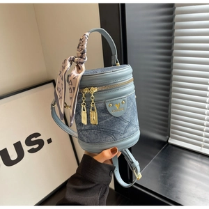 Détail du sac seau en denim avec texture matelassée, finitions cuir et foulard en soie