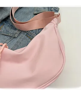 Detailed close-up of light pink nylon cross-body bag with soft textured fabric