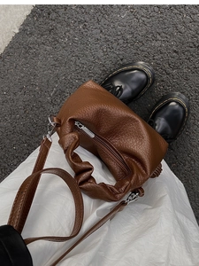 Détail du sac en cuir marron foncé avec texture litchi et poignée plissée élégante