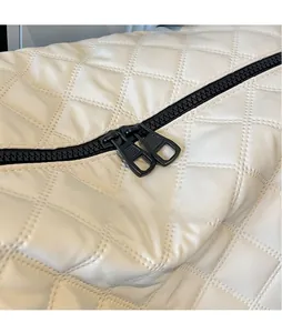 Details von glattem Metallreißverschluss und Rautensteppung auf der weißen Ledertasche