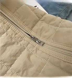 Detail of khaki quilted canvas bag featuring a smooth silver metal zipper and diamond pattern
