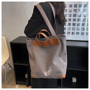 Detalle del bolso tote de lona gris con ribete de cuero marrón y correa ancha de tela