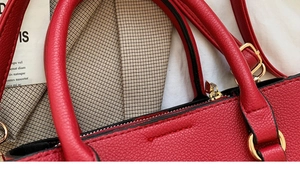 Close-up of red lychee texture leather handbag with golden zipper and D-ring hardware