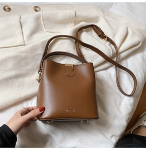 Detailed close-up of a brown leather bucket bag with gold hardware and logo branding
