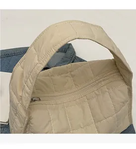 Close-up of beige quilted tote bag showing sturdy handle and white stitching details