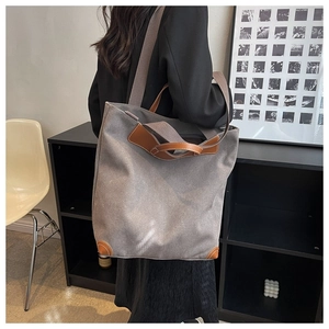 Detail of grey canvas tote bag with brown leather handles and adjustable shoulder strap