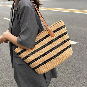 Large striped woven straw tote bag with brown leather shoulder straps for beach travel