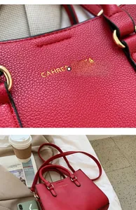 Detailed macro view of red lychee grain leather texture and gold hardware on tote bag